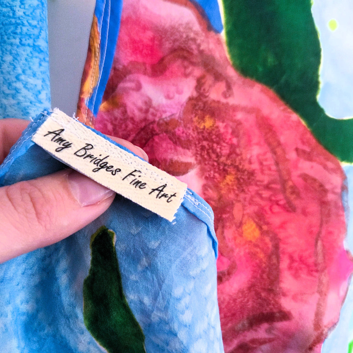 Detail of Rosewater Sky silk scarf showing hand rolled hem and secure stitching and Art by Amy Bridges tag